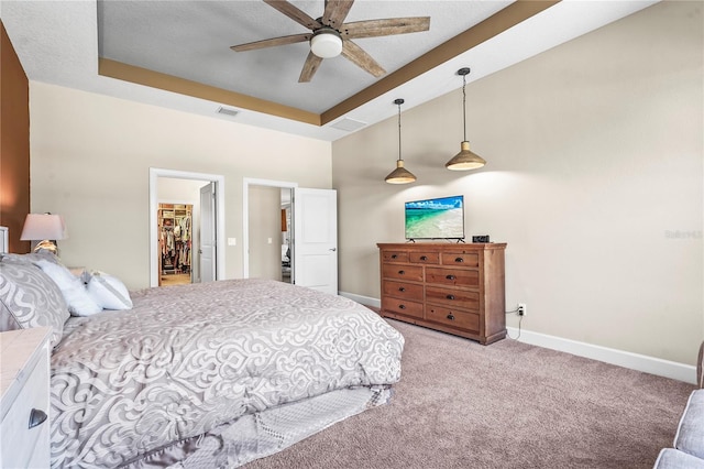 bedroom with light carpet, a spacious closet, a raised ceiling, and baseboards