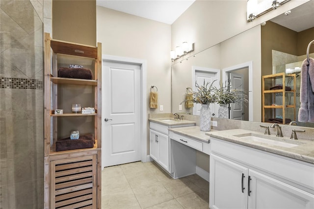 bathroom with double vanity, a tile shower, a sink, and tile patterned floors