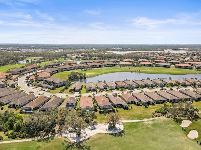 drone / aerial view featuring a residential view, view of golf course, and a water view