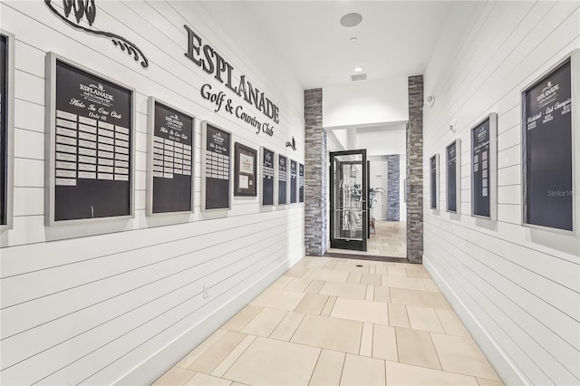 hall with tile patterned flooring, mail area, and wooden walls