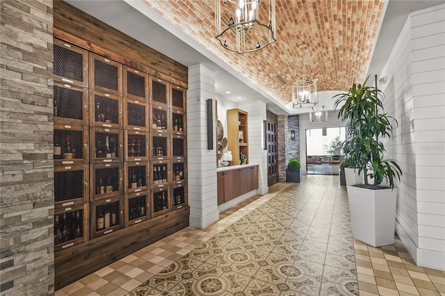 wine room featuring brick ceiling, light tile patterned flooring, a notable chandelier, and brick wall