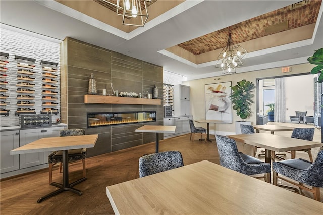 dining room with a chandelier, a tray ceiling, a fireplace, and baseboards