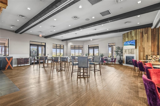 dining room with a large fireplace, visible vents, beamed ceiling, and wood finished floors