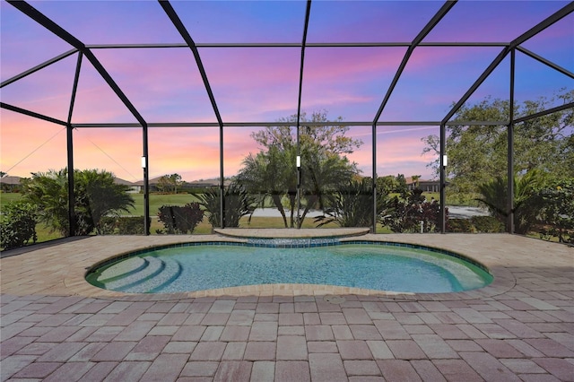 pool at dusk with a patio and glass enclosure