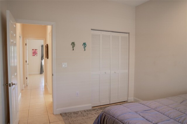 bedroom with light tile patterned floors, a closet, and baseboards