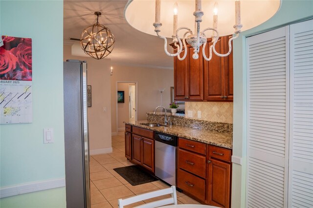 kitchen with appliances with stainless steel finishes, decorative light fixtures, a notable chandelier, stone counters, and a sink