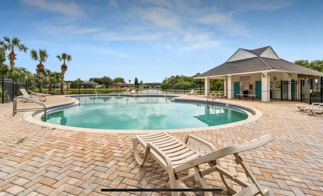 pool with a patio and fence