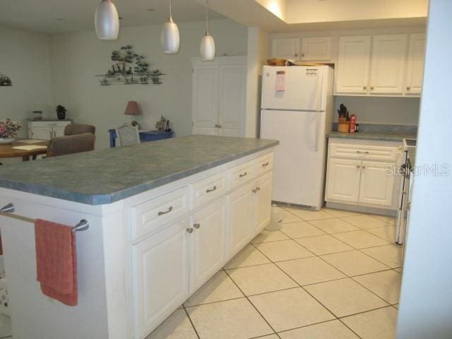 kitchen with dark countertops, a center island, freestanding refrigerator, and white cabinetry