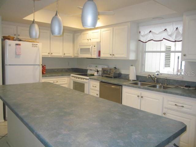 kitchen with dark countertops, white appliances, white cabinetry, and a sink