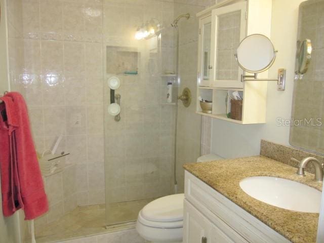 full bath with a stall shower, vanity, and toilet