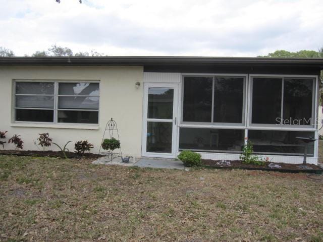 back of property with a lawn and stucco siding