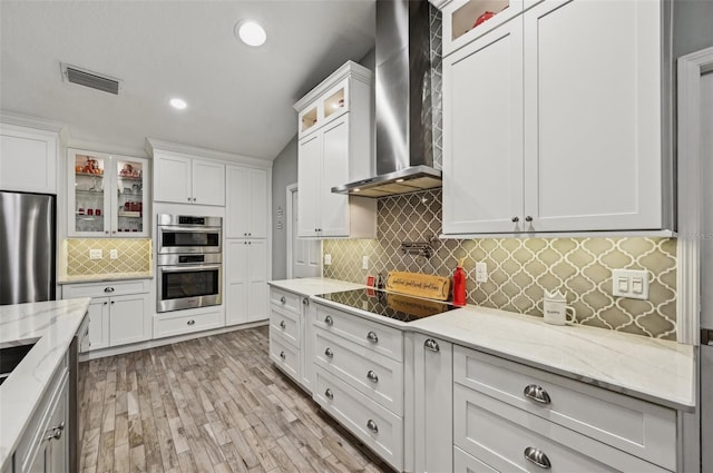 7415 36th Ave E, Palmetto, FL 34221 - kitchen featuring stainless steel appliances, white cabinetry, wall chimney range hood, and light stone counters