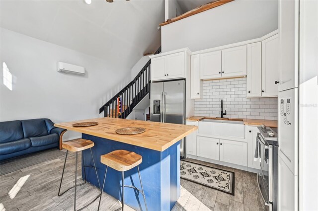 7415 36th Ave E, Palmetto, FL 34221 - kitchen featuring appliances with stainless steel finishes, butcher block countertops, white cabinetry, sink, and a kitchen breakfast bar