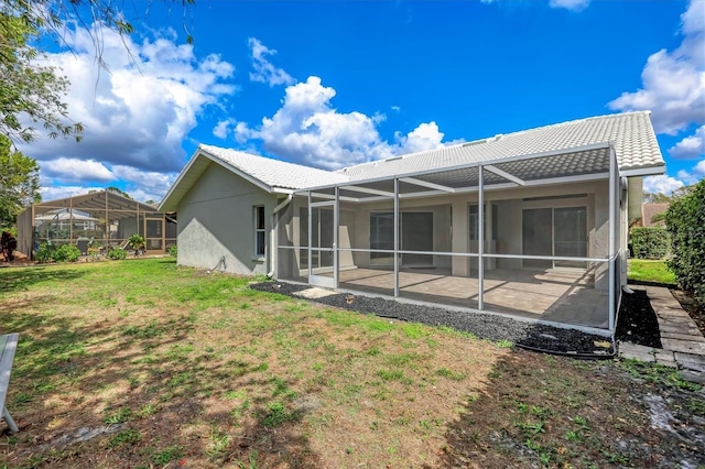 rear view of house featuring a yard, a patio, and glass enclosure