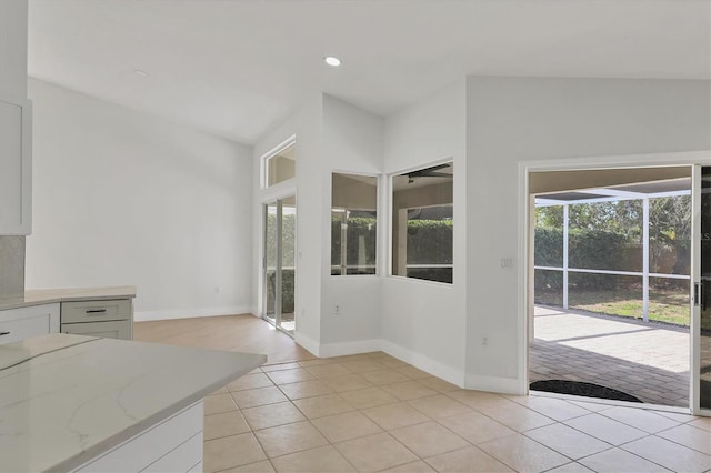 interior space with white cabinetry, light tile patterned floors, and light stone counters