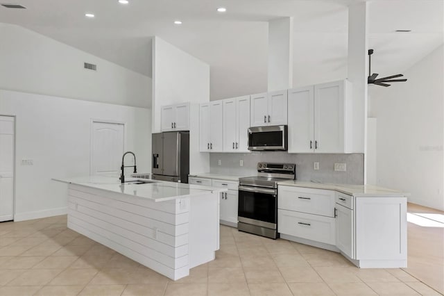 kitchen with white cabinetry, stainless steel appliances, sink, and a center island with sink