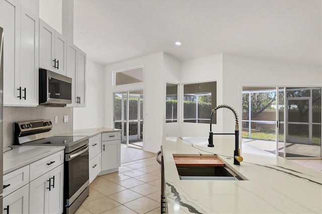 kitchen featuring sink, white cabinetry, stainless steel appliances, light stone countertops, and light tile patterned flooring