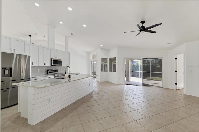 kitchen with lofted ceiling, white cabinetry, light stone counters, a kitchen island, and stainless steel appliances