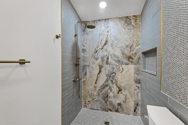 bathroom featuring toilet, tile walls, and a tile shower