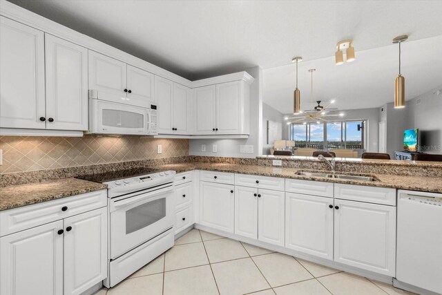 kitchen featuring white appliances, a sink, white cabinetry, open floor plan, and hanging light fixtures