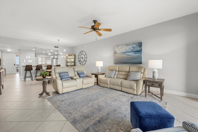 living area with light tile patterned flooring, baseboards, and ceiling fan with notable chandelier