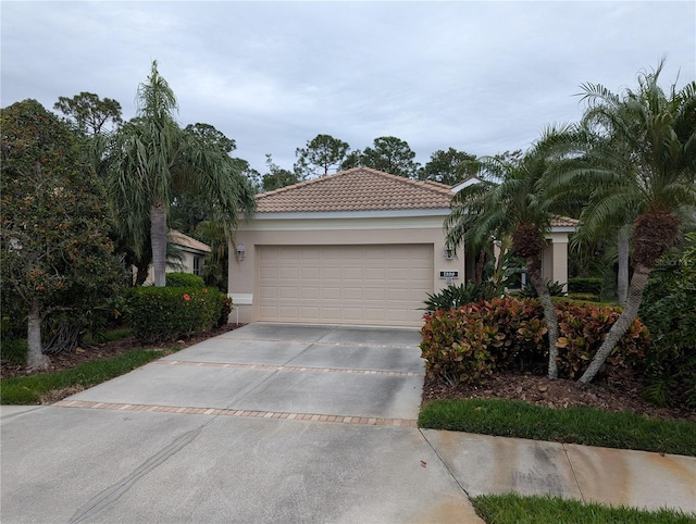 view of front of home with a garage, concrete driveway, a tiled roof, and stucco siding