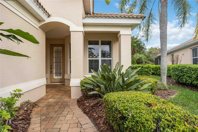 property entrance featuring a tile roof and stucco siding