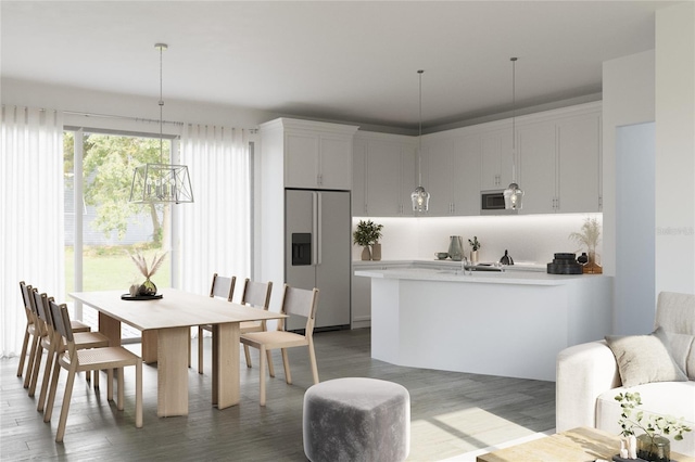 kitchen featuring pendant lighting, stainless steel appliances, hardwood / wood-style floors, and white cabinets