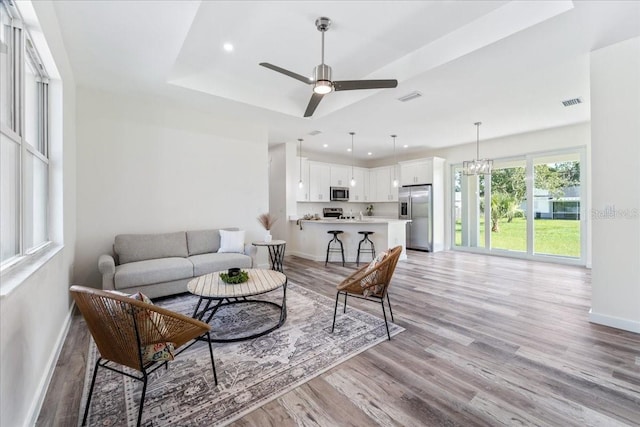 18290 Grace Ave, Port Charlotte, FL 33948 - living area with light wood-style floors, ceiling fan, a chandelier, recessed lighting, and a tray ceiling