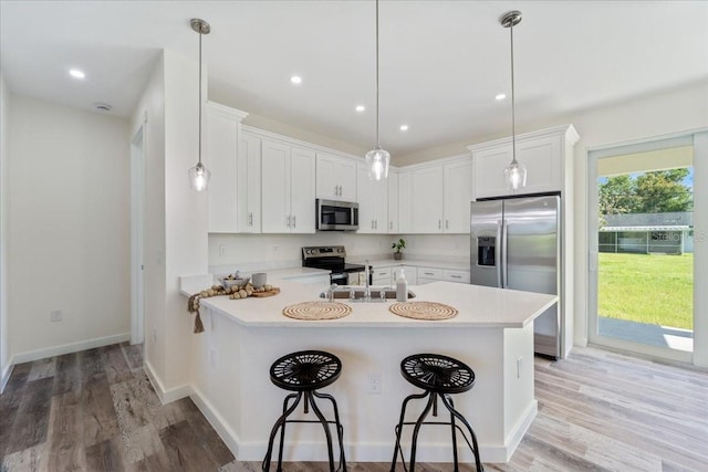 18290 Grace Ave, Port Charlotte, FL 33948 - kitchen featuring stainless steel appliances, a peninsula, light countertops, a breakfast bar, and light wood finished floors