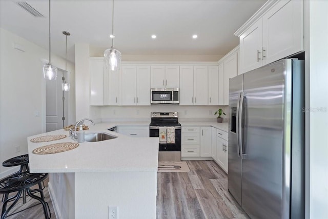 18290 Grace Ave, Port Charlotte, FL 33948 - kitchen with appliances with stainless steel finishes, a peninsula, light wood-type flooring, white cabinets, and pendant lighting