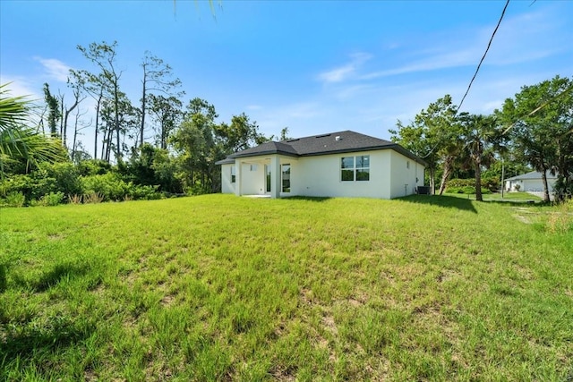 18290 Grace Ave, Port Charlotte, FL 33948 - back of house with stucco siding and a yard