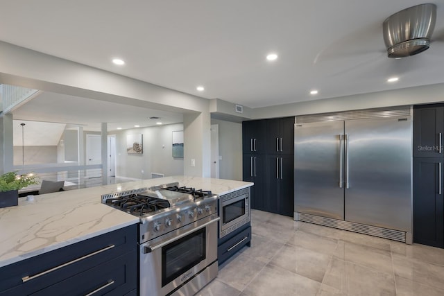 kitchen featuring built in appliances, light stone counters, and light tile patterned floors