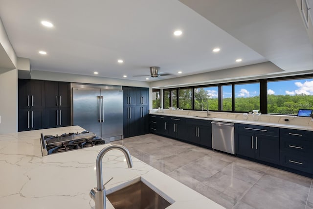 kitchen featuring stainless steel appliances, light stone countertops, sink, and plenty of natural light