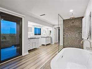 bathroom featuring vanity, wood-type flooring, and a tub