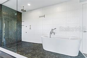 bathroom with tile walls, sink, and separate shower and tub