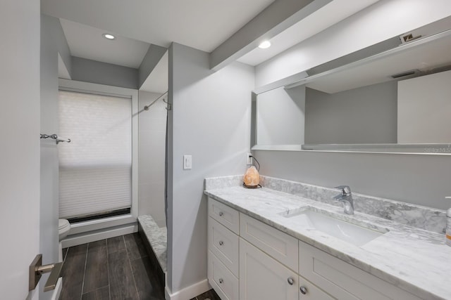 bathroom with hardwood / wood-style flooring, vanity, a shower, and toilet