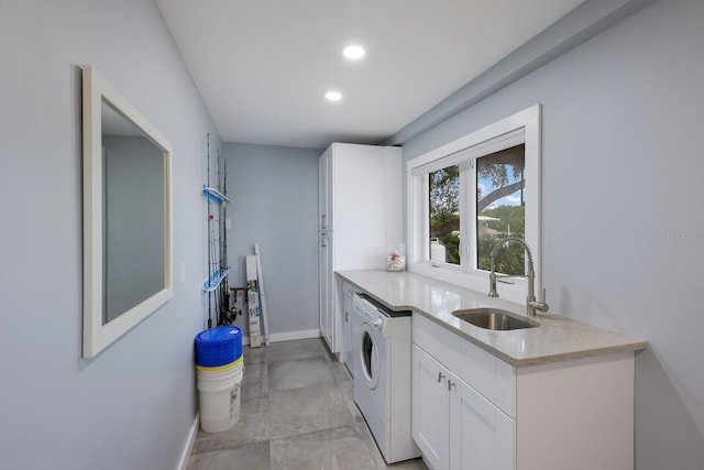 clothes washing area with separate washer and dryer, sink, and cabinets