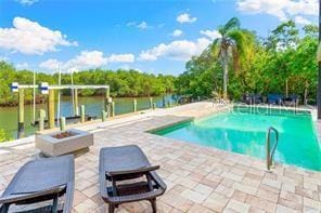 view of pool featuring a water view, an outdoor fire pit, and a patio area