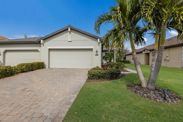 view of front of house with stucco siding, a front lawn, decorative driveway, and a garage