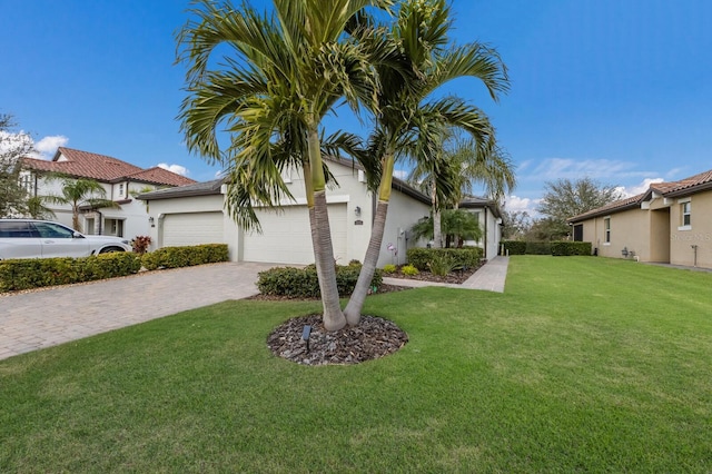 view of front of house with a garage, decorative driveway, a front lawn, and stucco siding