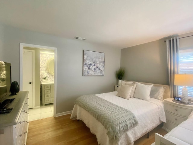 bedroom featuring light wood-type flooring and ensuite bathroom