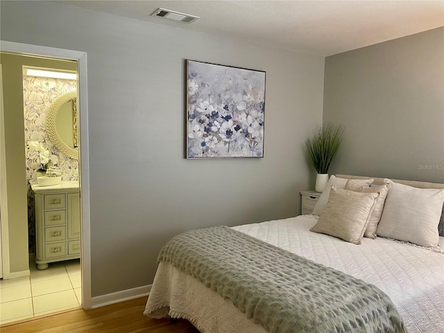 bedroom with light hardwood / wood-style floors and connected bathroom