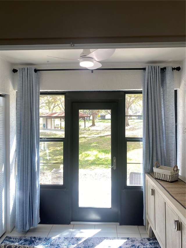 entryway featuring ceiling fan, plenty of natural light, and light tile patterned flooring