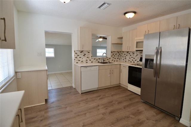 kitchen with hardwood / wood-style flooring, white appliances, sink, and backsplash