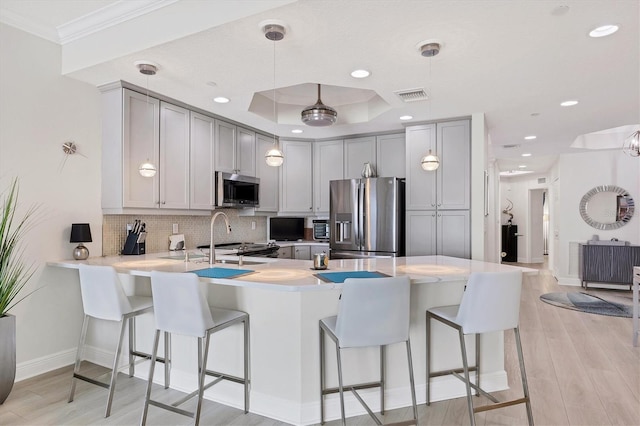 kitchen with decorative light fixtures, appliances with stainless steel finishes, gray cabinets, and kitchen peninsula