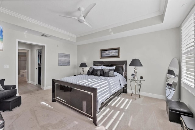 carpeted bedroom featuring a tray ceiling, ornamental molding, and ceiling fan