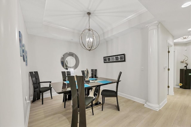 dining area with a raised ceiling, light wood-type flooring, and decorative columns