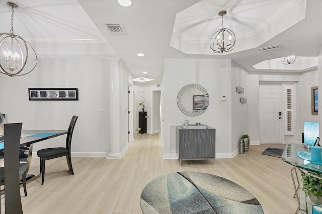 dining space featuring light wood-type flooring, a chandelier, a tray ceiling, and crown molding