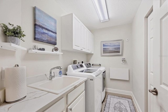 washroom with washing machine and clothes dryer, sink, cabinets, and a textured ceiling